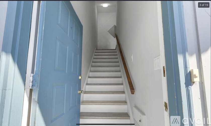 A blue door is on the left and a staircase is on the right.