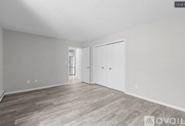 A spacious room with wood flooring and white walls.