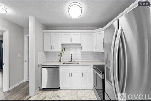 A modern kitchen with white cabinets and stainless steel appliances.