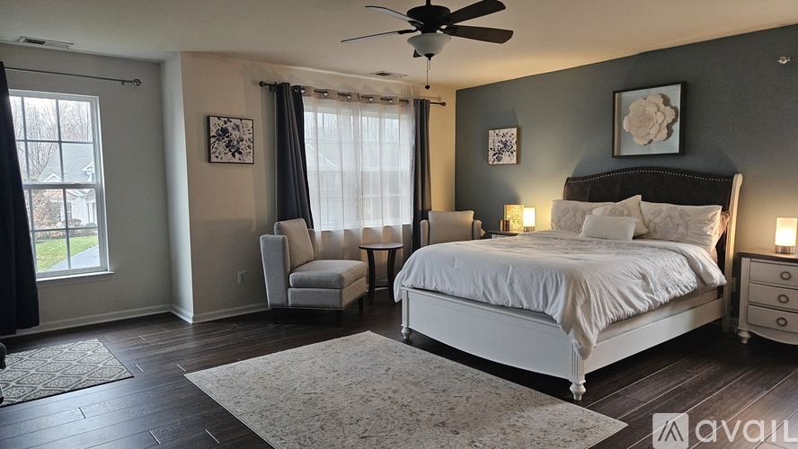 A bedroom with a large bed, a chair, and a ceiling fan.
