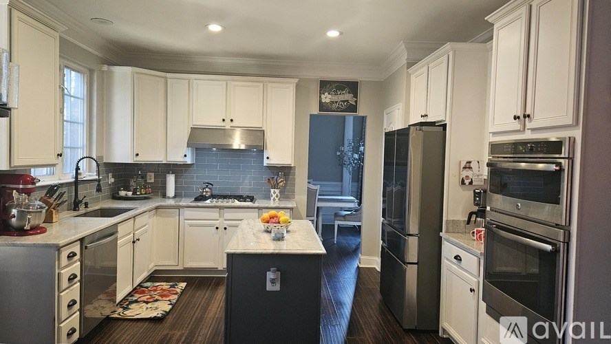 A modern kitchen with white cabinets and stainless steel appliances.