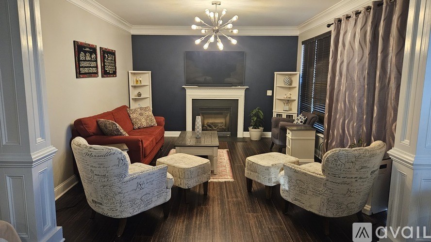 A living room with a red couch, two chairs, and a fireplace.