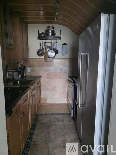 A kitchen with a refrigerator, sink, and wooden cabinets.