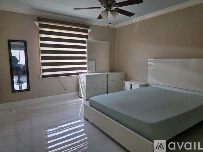 A bedroom with a bed, a ceiling fan, and a window with blinds.