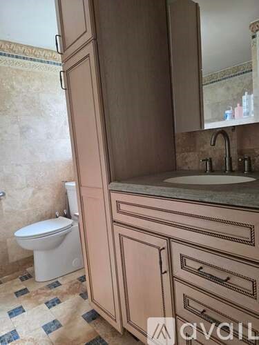 A bathroom with a toilet, sink, and cabinets.