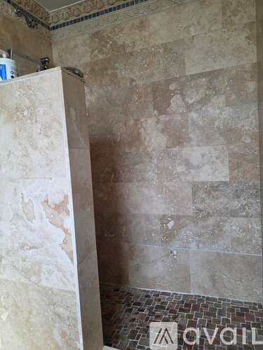 A bathroom with a tiled floor and walls covered in beige tiles.