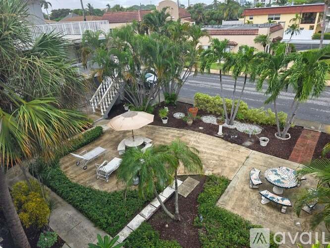 A patio with a table and chairs surrounded by greenery.