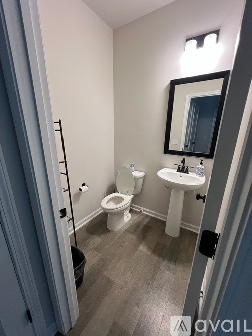 A bathroom with a toilet, sink, and mirror.