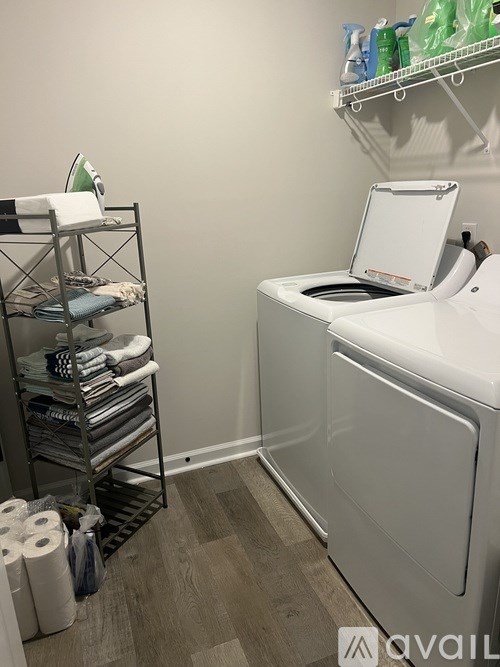 A white washing machine sits next to a rack of folded towels.