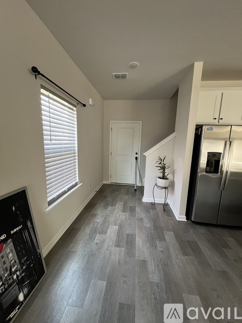 A room with a grey floor and a fridge in the corner.