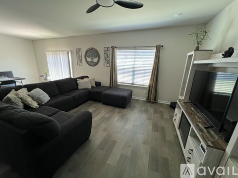 A living room with a black couch and a television on a wooden stand.