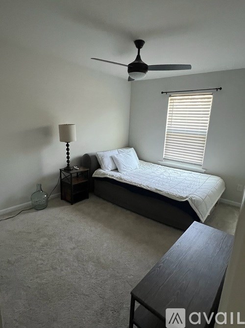 A bedroom with a bed, nightstand, and window.