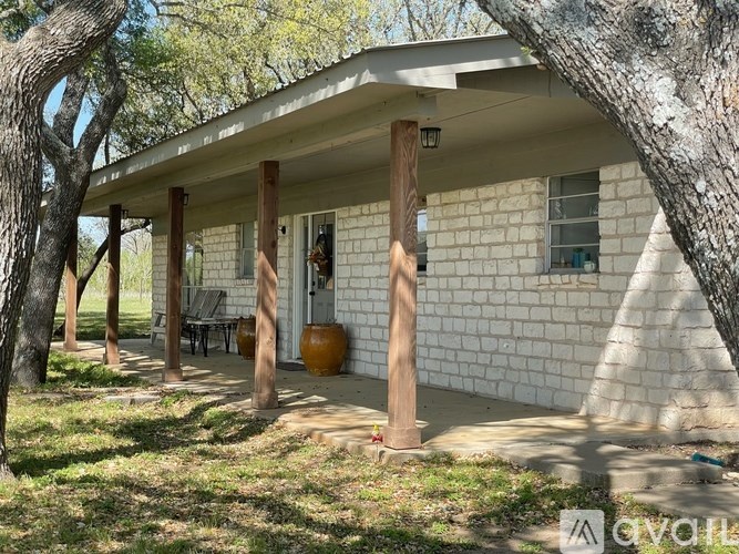 A white house with a porch and a tree in front.