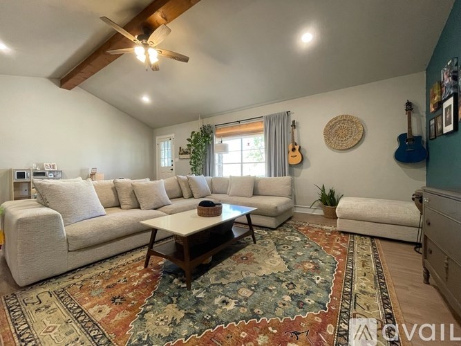 A living room with a white couch, a rug, and a ceiling fan.