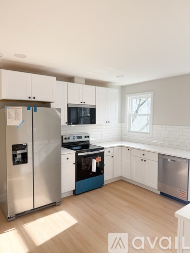 A kitchen with white cabinets and a stainless steel refrigerator.