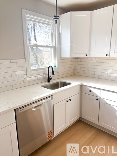 A kitchen with white cabinets and a stainless steel dishwasher.