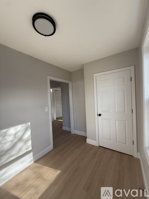 A room with a white door and wooden flooring.