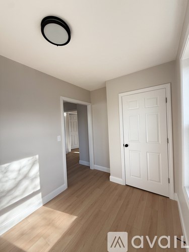 A room with a white door and a window with sunlight coming through.