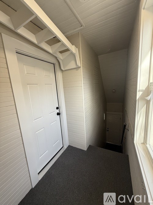 A white door is in a hallway with a carpeted floor.