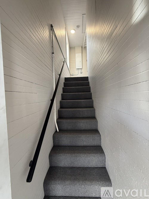 A staircase with a black handrail and grey steps.