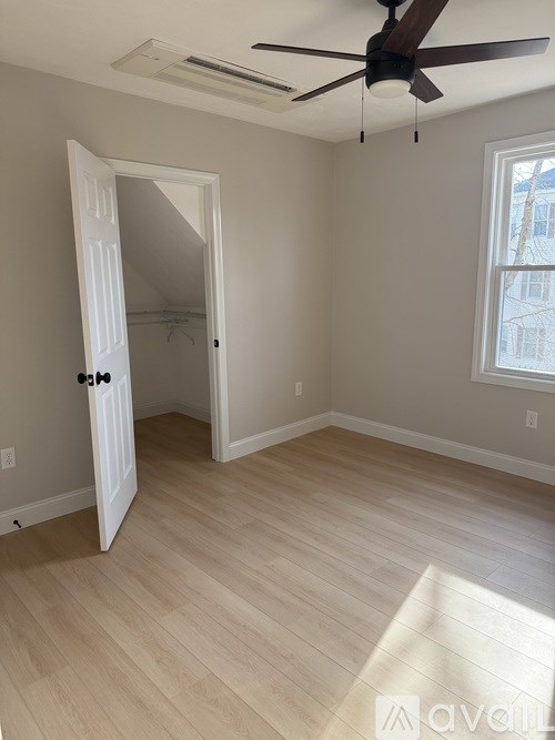 A room with a ceiling fan and a door leading to a hallway.