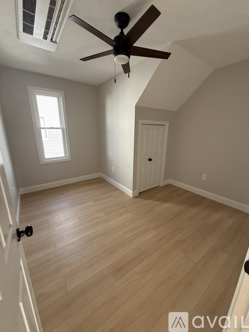 A room with a ceiling fan and wooden flooring.