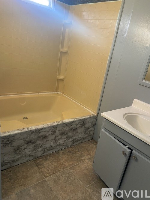 A bathroom with a marble edge tub and a white sink.