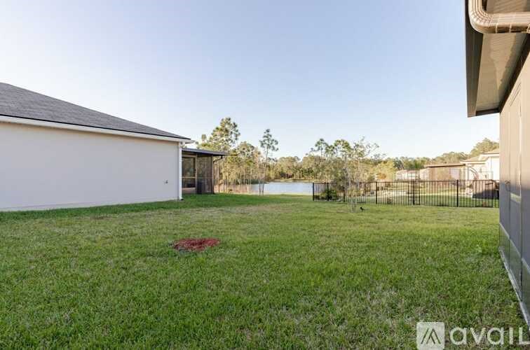A white house with a black roof and a fence in front of it.