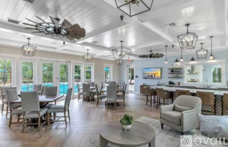 A spacious living room with a dining area and a pool in the background.