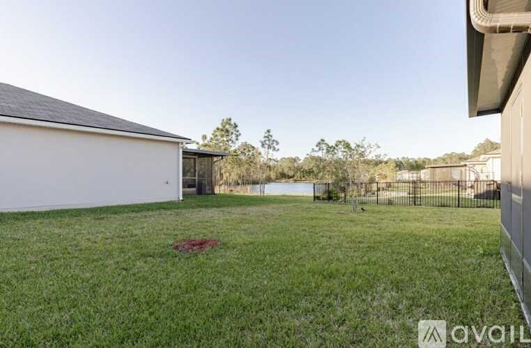 A white house with a black roof is surrounded by a green lawn.