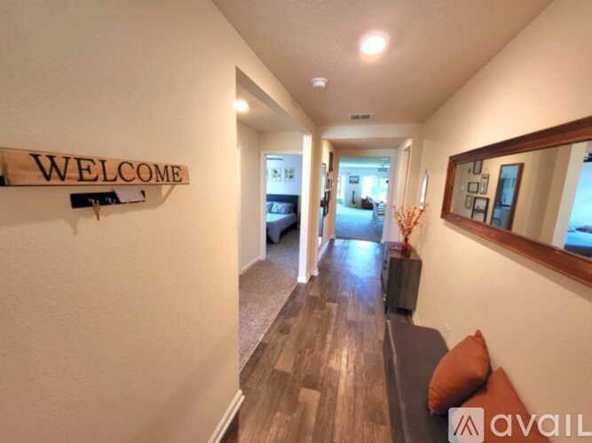 A hallway with a wooden floor and a "Welcome" sign on the wall.