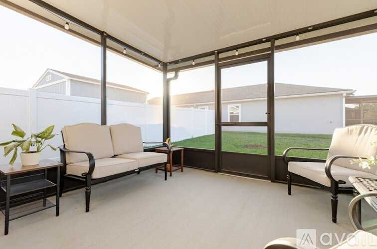 A patio with a couch, chairs, and a table with a potted plant on it.