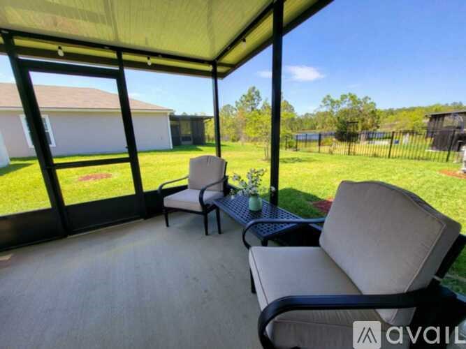 A covered patio with two chairs and a table.