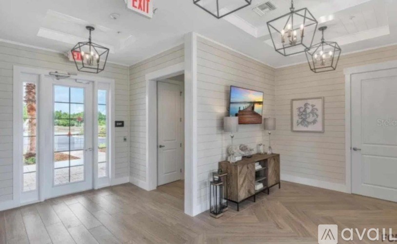 A room with a white door, a window, and a chandelier.