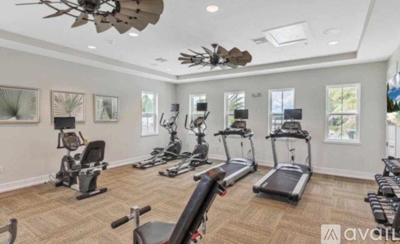 A spacious home gym with various exercise equipment and a ceiling fan.