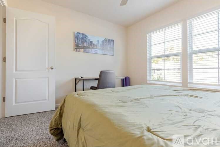 A bedroom with a bed, a chair, and a painting on the wall.