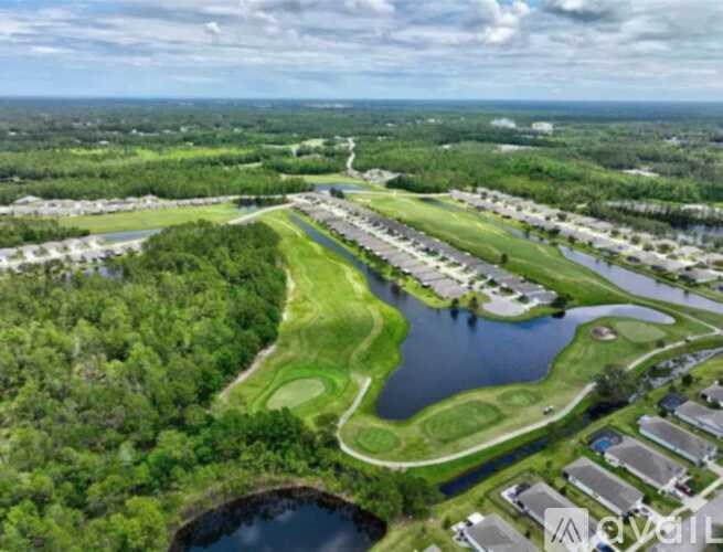 A bird's eye view of a residential area with a lake and greenery.