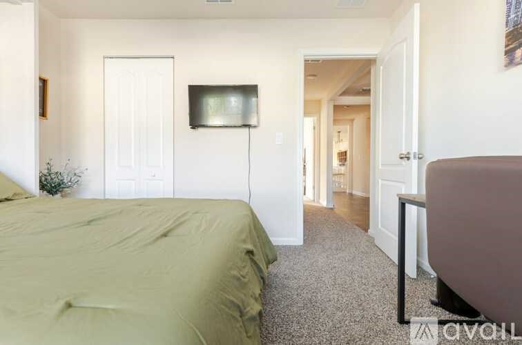 A bedroom with a bed, a flat screen TV, and a carpeted floor.