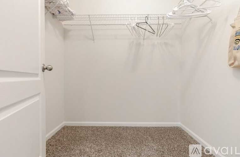 A small, empty room with a carpeted floor and a white door.