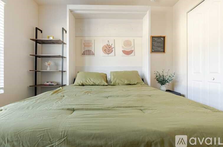 A bedroom with a bed, pillows, and a wall-mounted shelf.