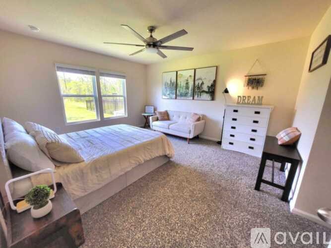 A bedroom with a bed, a couch, a coffee table, and a ceiling fan.
