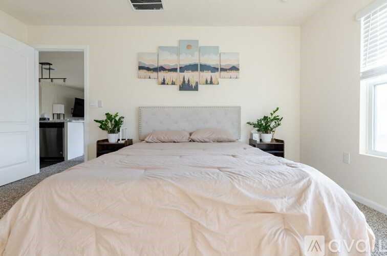 A bedroom with a large bed and a painting on the wall.