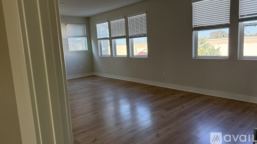 A room with wooden flooring and three windows.