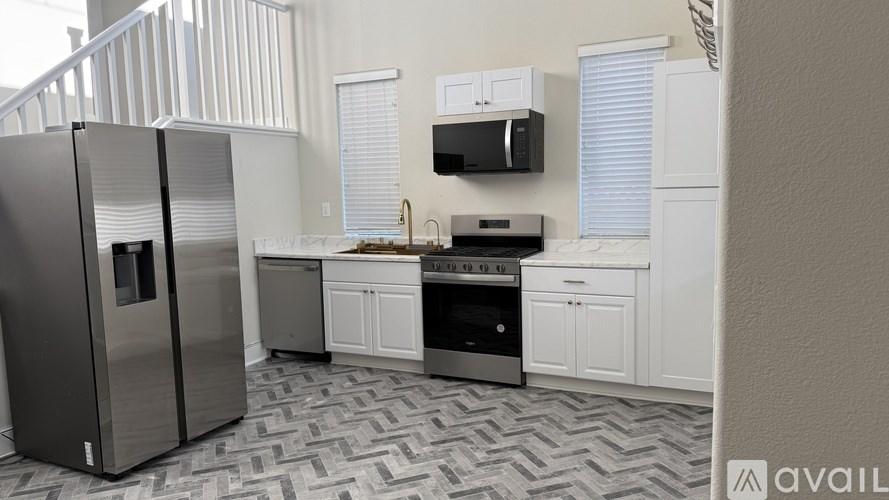 A kitchen with a black fridge and stove top oven.