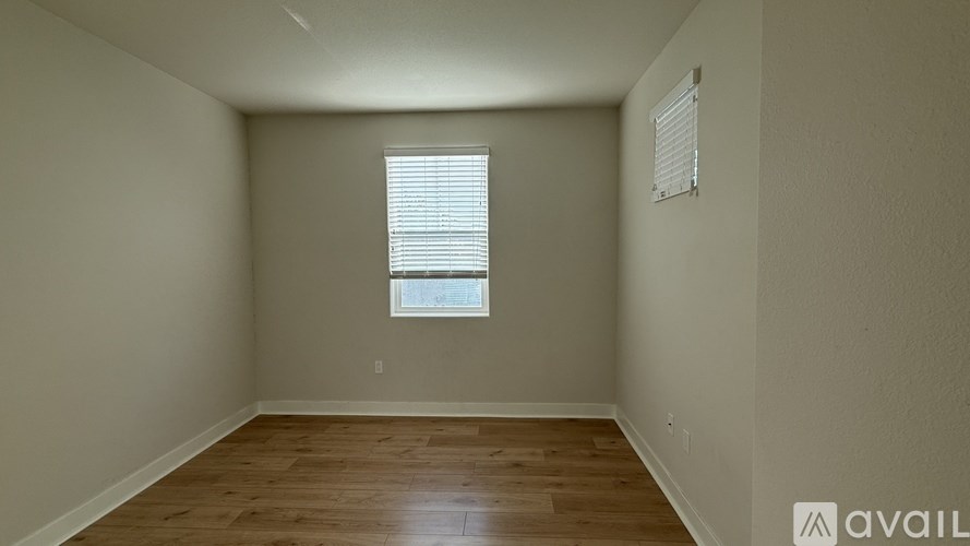 A room with wooden flooring and a window with blinds.
