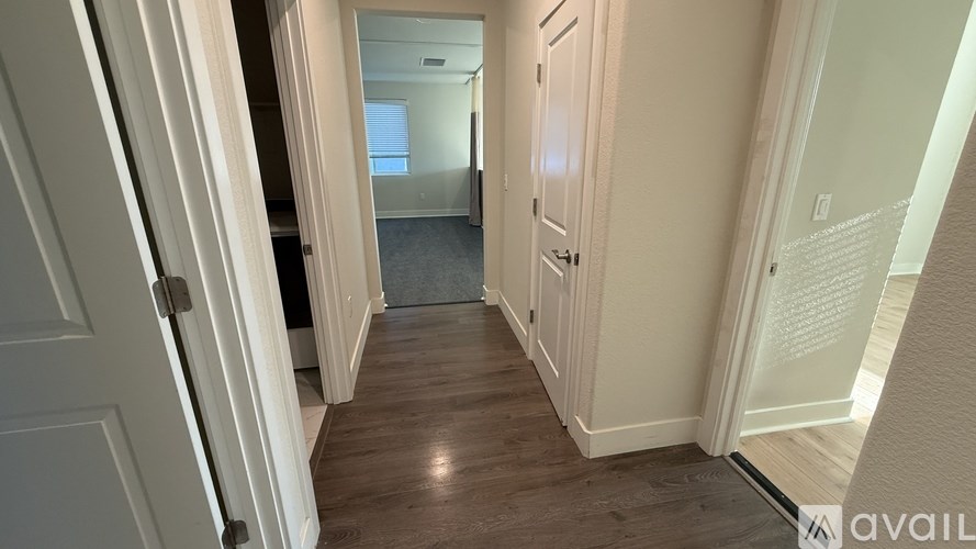 A hallway with wooden floors and white walls.