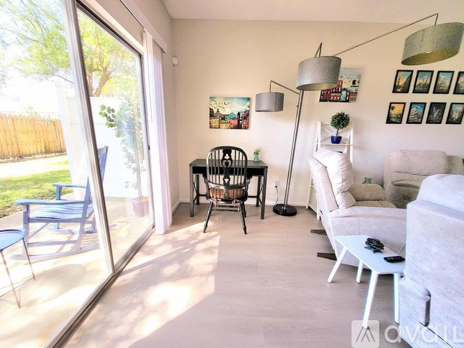 A living room with a white couch, a black chair, and a white coffee table.