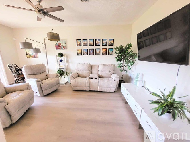 A living room with a white couch, a white coffee table, and a TV on the wall.