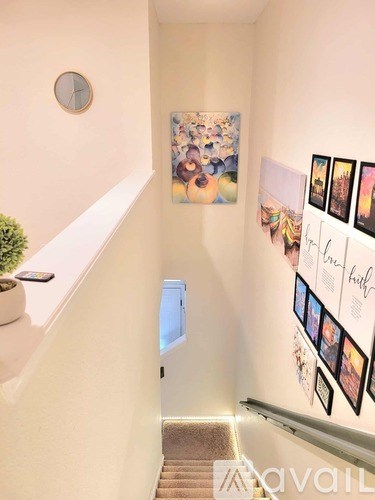 A hallway with a staircase and pictures on the wall.