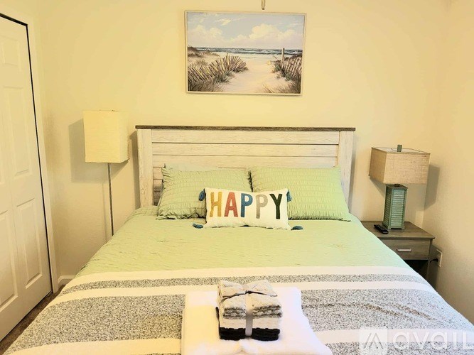 A bed with a green pillow and a pillow with the word "HAPPY" on it.
